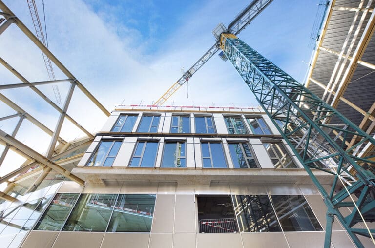 Gevelbouwproject met kraan en moderne staalconstructie in aanbouw bij Tholin Gevelbouw, met focus op de glazen gevelpanelen en constructieve precisie.
